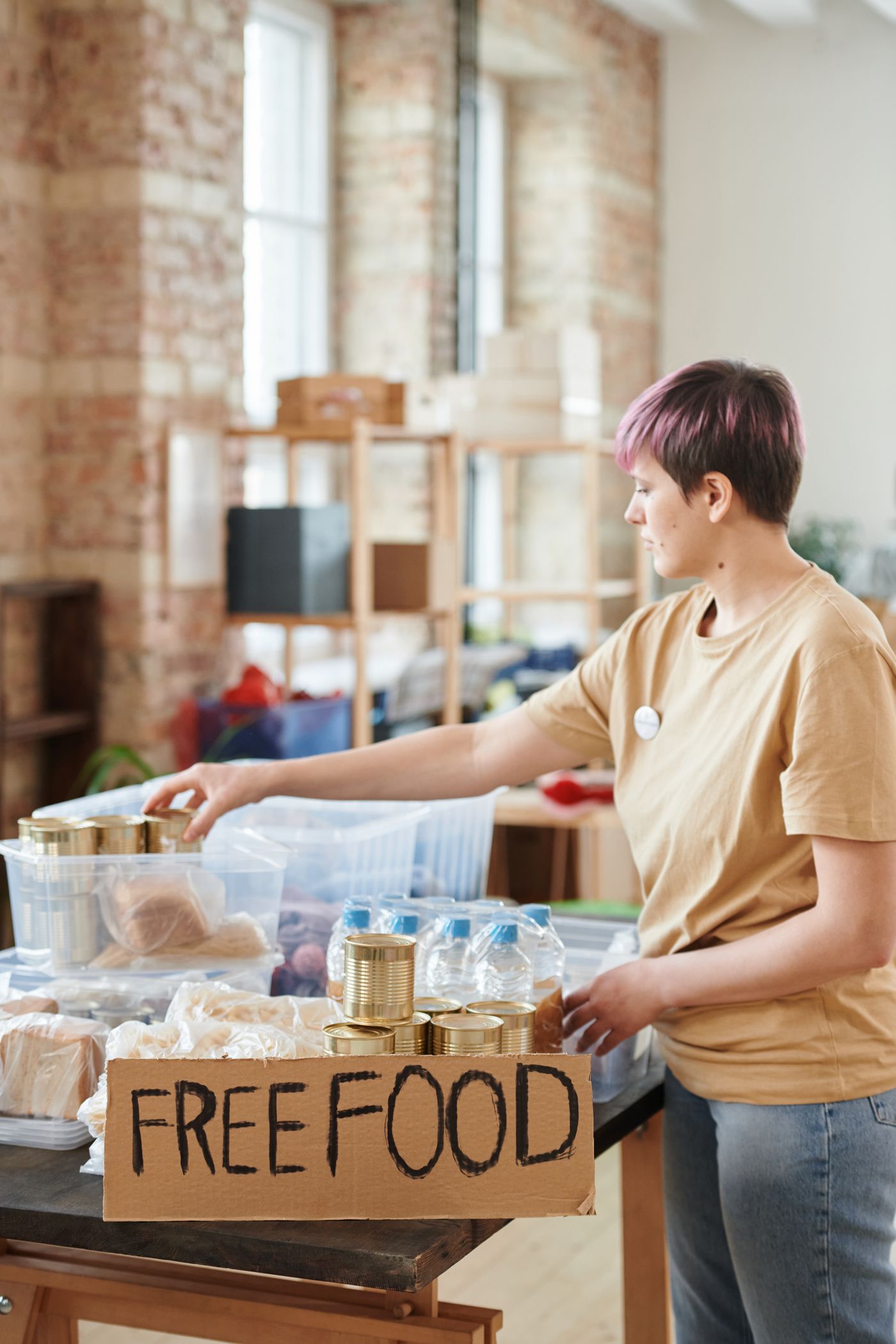 A volunteer arranging free food on a community table